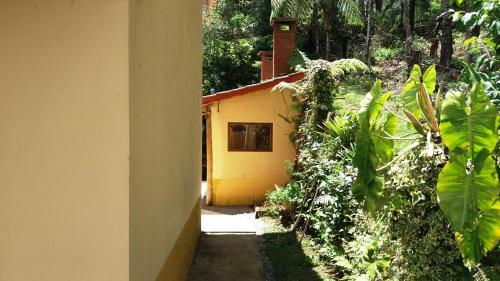 a house with a yellow door and some plants at Refúgio do Azzi in Monte Verde
