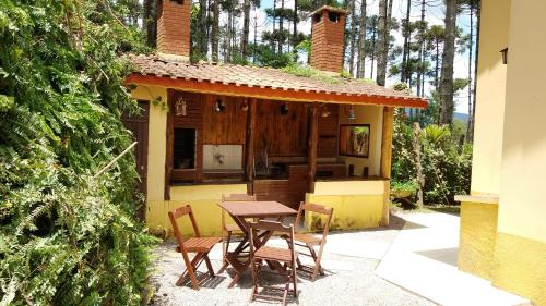 a table and chairs in front of a house at Refúgio do Azzi in Monte Verde
