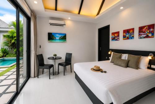 a bedroom with a bed and a table and chairs at Pool Villa Clos Vougeot Tropical Vibe in Ban Saiyuan (1)