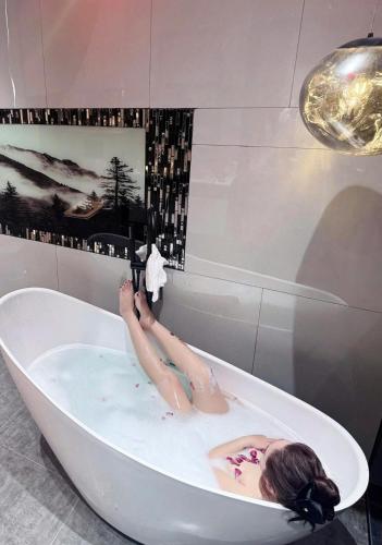 a woman laying in a bath tub with her legs up at Lyn's Hotel Da Lat in Da Lat
