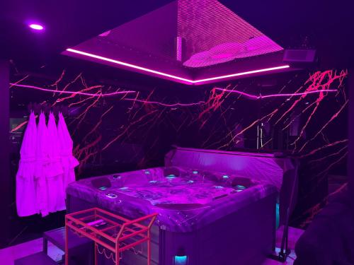 a room with a hot tub with purple lighting at La Suite Prestige in Saint-Quentin