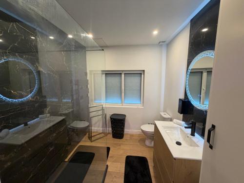 a bathroom with a sink and a toilet and mirrors at La Suite Prestige in Saint-Quentin