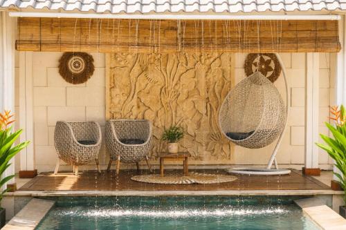 a pool with two chairs and a table and a wall at Empat Bintang Villas in Uluwatu
