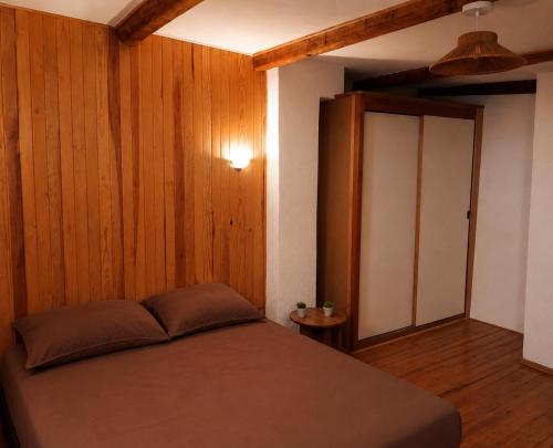 a bedroom with a bed and a wooden wall at Le cocon de Barcelonnette in Barcelonnette