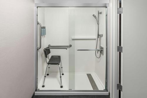 a glass shower door with a chair in a bathroom at Courtyard by Marriott Flint Grand Blanc in Flint
