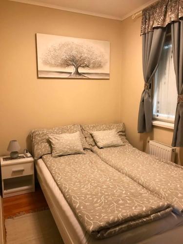 a bed in a bedroom with a tree on the wall at Kincs apartman in Győr