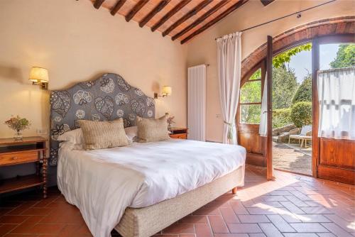 a bedroom with a large bed and a large window at Borgo Vescine in Radda in Chianti
