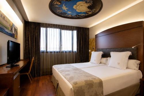 a bedroom with a bed and a desk and a television at Hotel Sancho Abarca Petit SPA in Huesca
