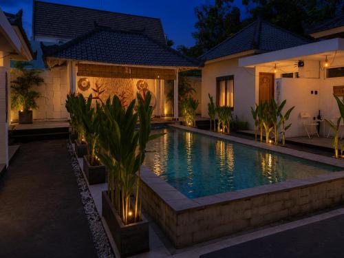 a swimming pool in the backyard of a house at night at Empat Bintang Villas in Uluwatu
