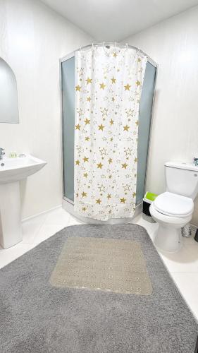 a bathroom with a shower curtain with a toilet and a sink at Guest House Ikathouse in Margilan