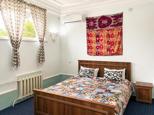 a bedroom with a bed and two windows at Guest House Ikathouse in Margilan