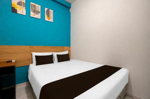a bedroom with a large bed with a blue wall at Collection O near Tunjungan Plaza formerly K15 in Kedongdong