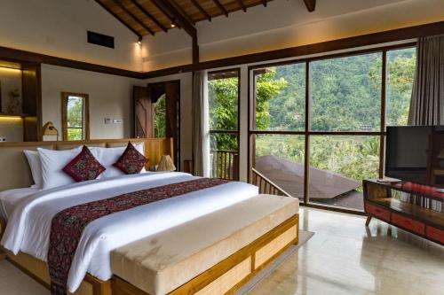 a bedroom with a large bed and large windows at Kropak Sidemen in Sidemen