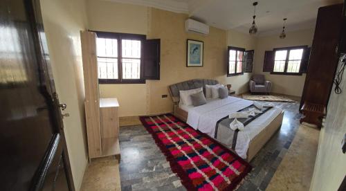 a bedroom with a bed and a couch and windows at Le Paisible Atlas in Marrakesh