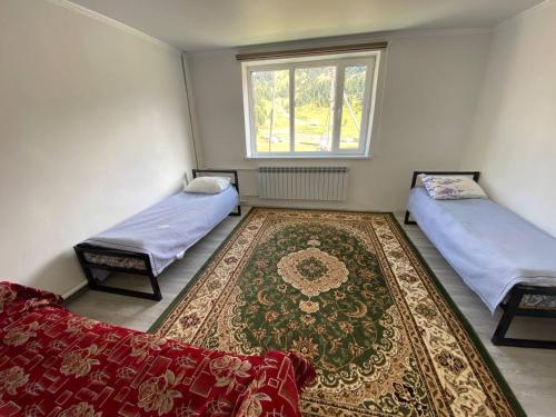 a room with two beds and a rug and a window at Syrgak in Dzhergalan