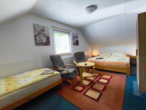 a room with two beds and a table and chairs at Penzion Pomněnka in Lipova Lazne
