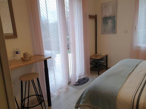 a bedroom with a bed and a stool next to a window at Chambre Terre et Mer-Millet in Gréville-Hague