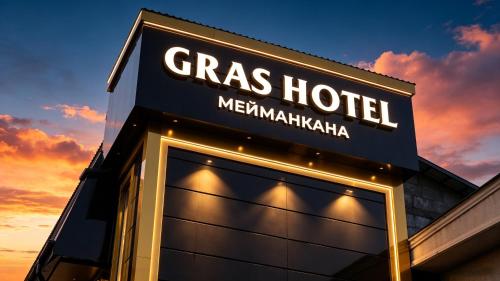 a sign for a grass hotel at sunset at Gras Business Hotel in Bishkek