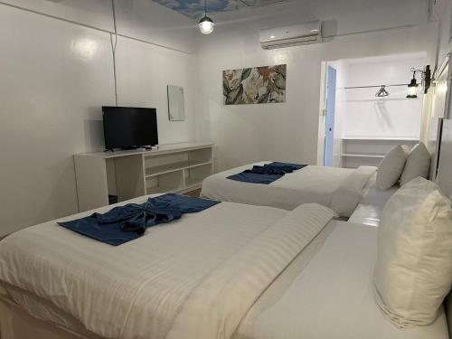 two beds in a white room with a tv at Bolabog Beach Resort in Boracay