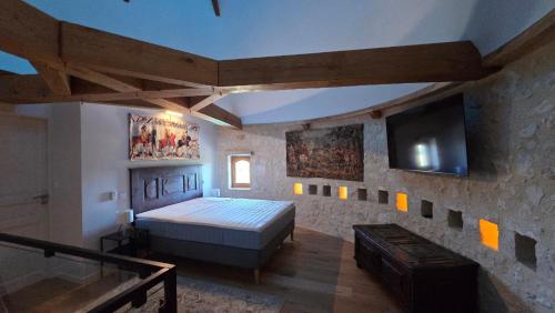 a bedroom with a bed and a flat screen tv at Colombier de Scandaillac in Saint-Eutrope-de-Born