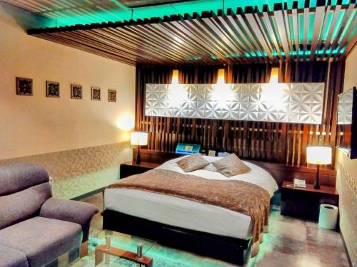 a bedroom with a bed and a chair and a couch at ホテルメイプル in Odate