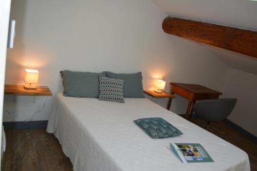 a bed with two pillows and a book on it at L'Entracte de Grignan pour 6 personnes in Grignan