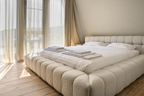 a large white bed in a room with windows at Sunken Tsaghkadzor in Tsaghkadzor