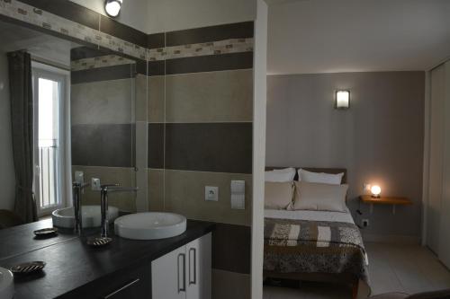 a bedroom with a bed and a bathroom with a sink at L'Entracte de Grignan pour 6 personnes in Grignan