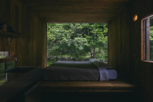 a window in a room with a bed in it at Earthboat Ueda Onsen in Nagano