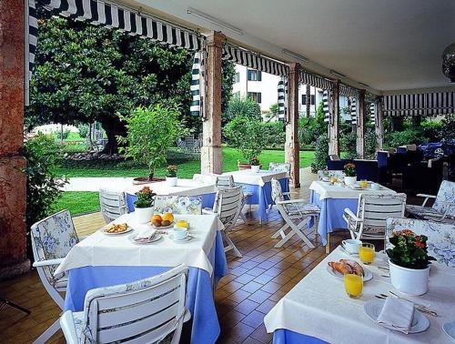 un restaurante con mesas y sillas blancas con comida. en Hotel Terminus, en Garda