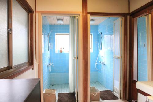 a blue bathroom with two toilets and a shower at Okayama Hostel Igusa in Hayashima