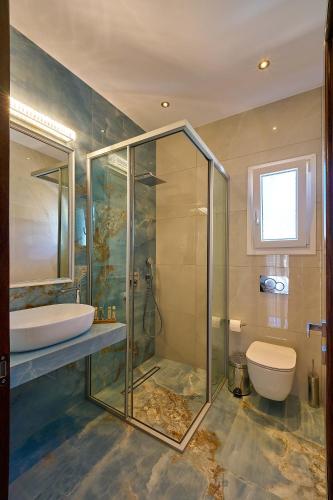 a bathroom with a glass shower and a toilet at Irida Home in Parga