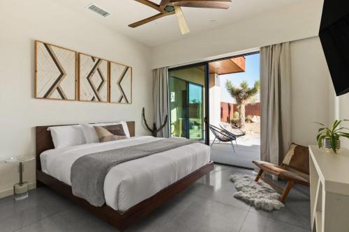 a bedroom with a large bed and a balcony at Windsong Modern compound w pool spa in Yucca Valley