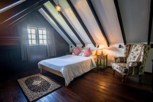 a bedroom with a bed and a chair and a window at The Bala's Holiday Chalet in Cameron Highlands