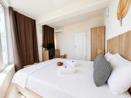 a bedroom with a large white bed with two pillows at Къща за гости Беглик Таш 2 in Primorsko
