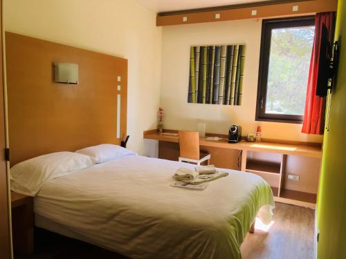 a bedroom with a bed and a desk and a window at Résidence Des Équipages in Le Castellet