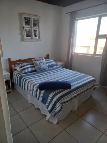a bedroom with a bed with a blue and white striped blanket at Arniston Cottage in Arniston