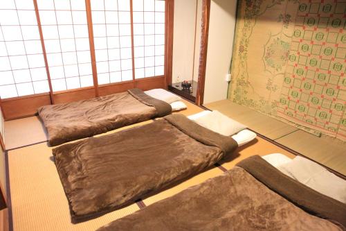 a room with three beds in a room with windows at Okayama Hostel Igusa in Hayashima