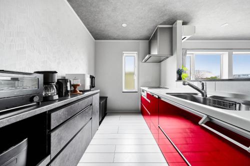 a kitchen with red cabinets and a sink at The Shelbourne Furano in Furano
