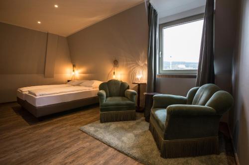 a hotel room with a bed and two chairs at Hotel Heimathafen in Lörrach