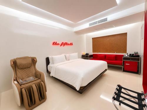 a bedroom with a bed and a red couch at The 50th Uthai Thani in Uthai Thani