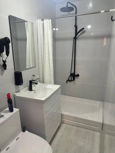 a white bathroom with a sink and a shower at JOMIY Guest House in Margilan