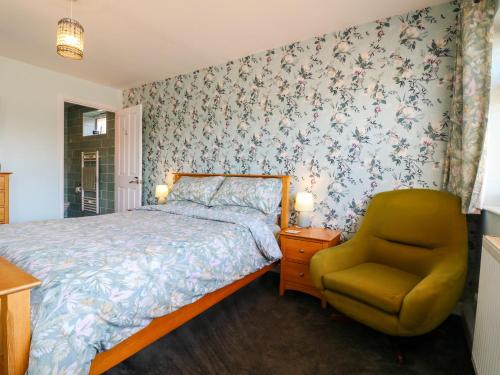 a bedroom with a bed and a chair at Pinecote Cottage in Nottingham