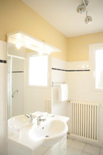 a white bathroom with a sink and a mirror at Au coeur du golfe in Sarzeau