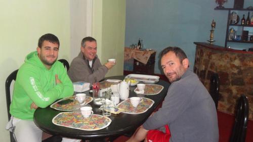 three men sitting at a table with plates of food at Sembuwatta Reach Homestay in Elkaduwa