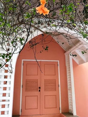 a pink door with a flower on top of it at Tobago Hibiscus Golf Villas & Appartments in Mount Irvine