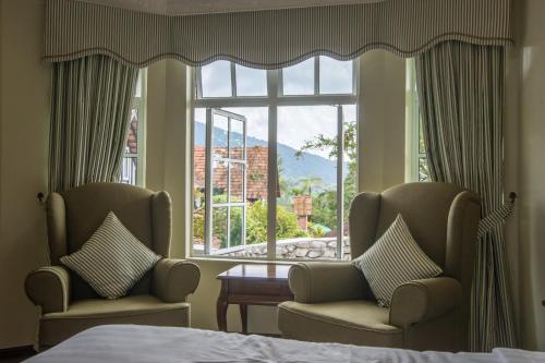 a bedroom with two chairs and a large window at The Bala's Holiday Chalet in Cameron Highlands