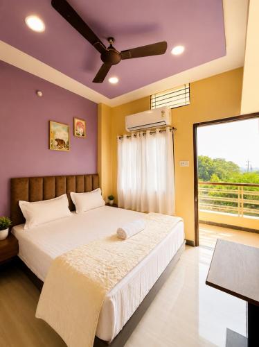 a bedroom with a large bed with a ceiling fan at Hotel Vrinda Maheshwar in Maheshwar