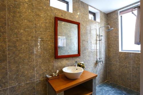 a bathroom with a sink and a shower with a mirror at An Bang Beach Dolphin Homestay in Hoi An