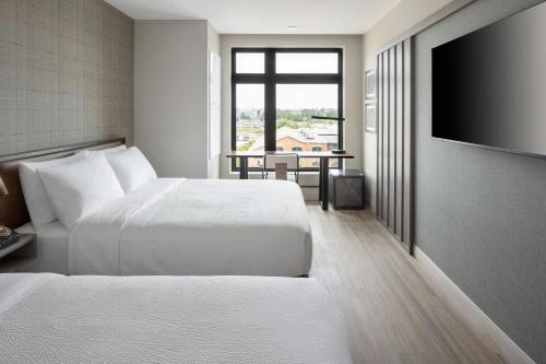 a hotel room with two beds and a flat screen tv at Moxy Portland Thompson's Point in Portland